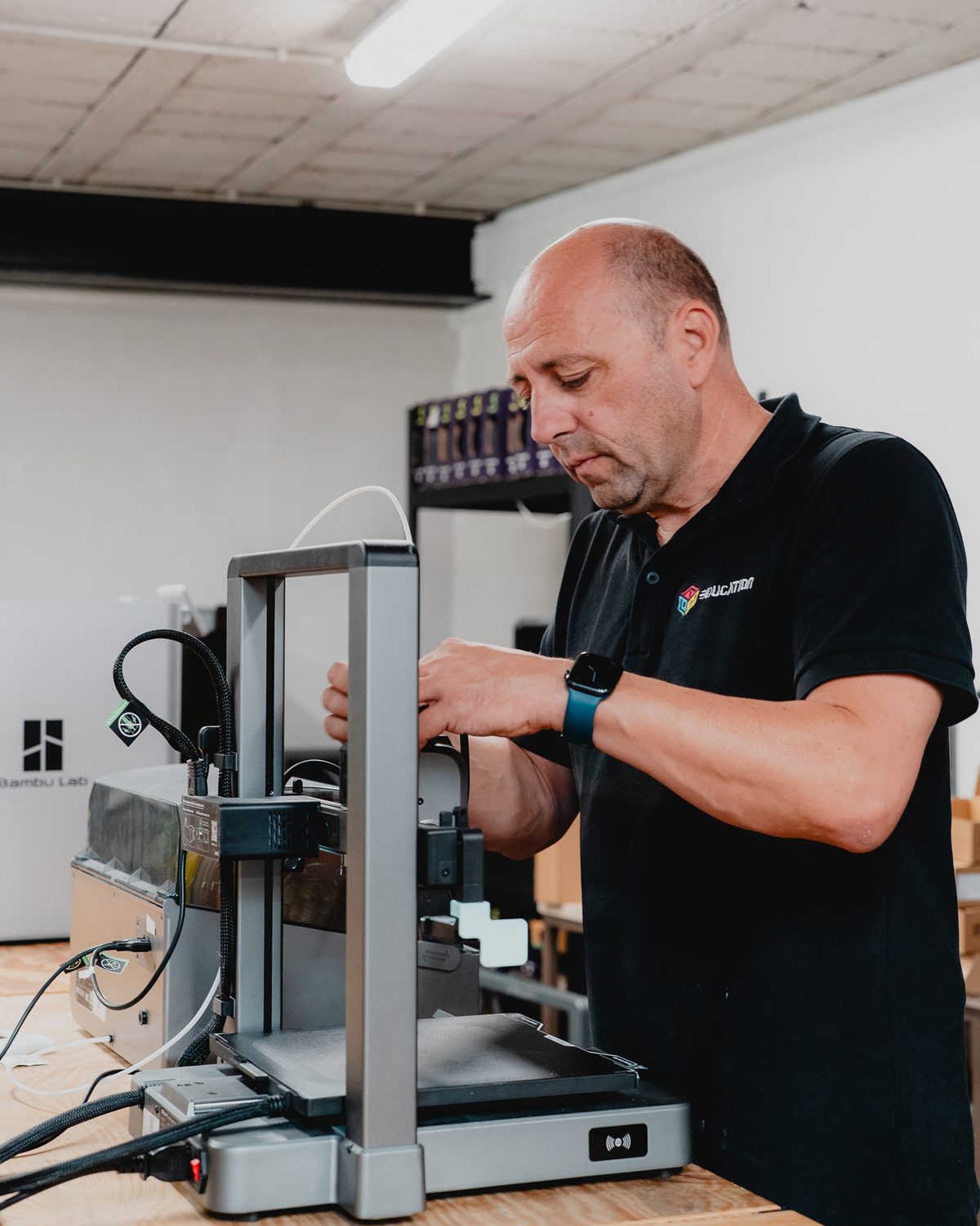 Een technicus werkt aan een opengewerkte 3D-printer aan de werkbank.