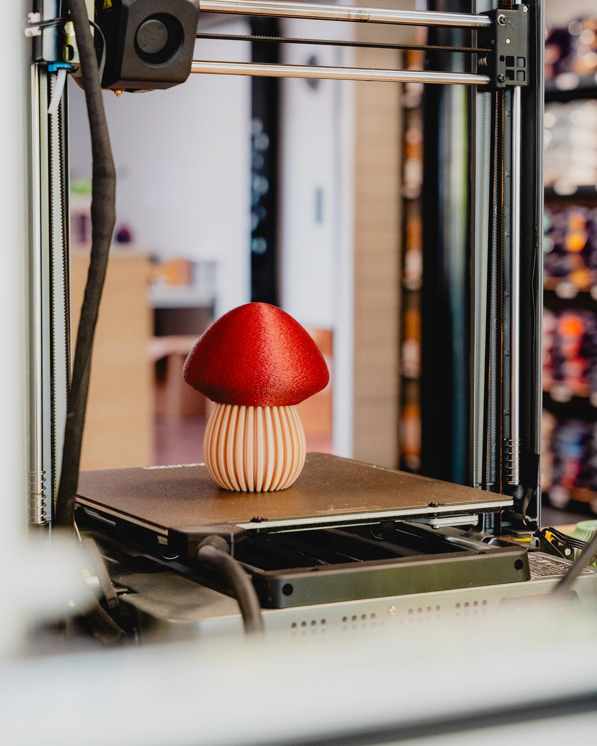 Een 3D-printer met een pas geprinte rode paddenstoel op het printbed.